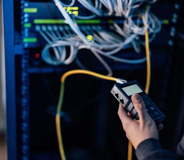 Working with rack-mount switches, ethernet cables and network tool kit, close-up. Holding network cable tester.